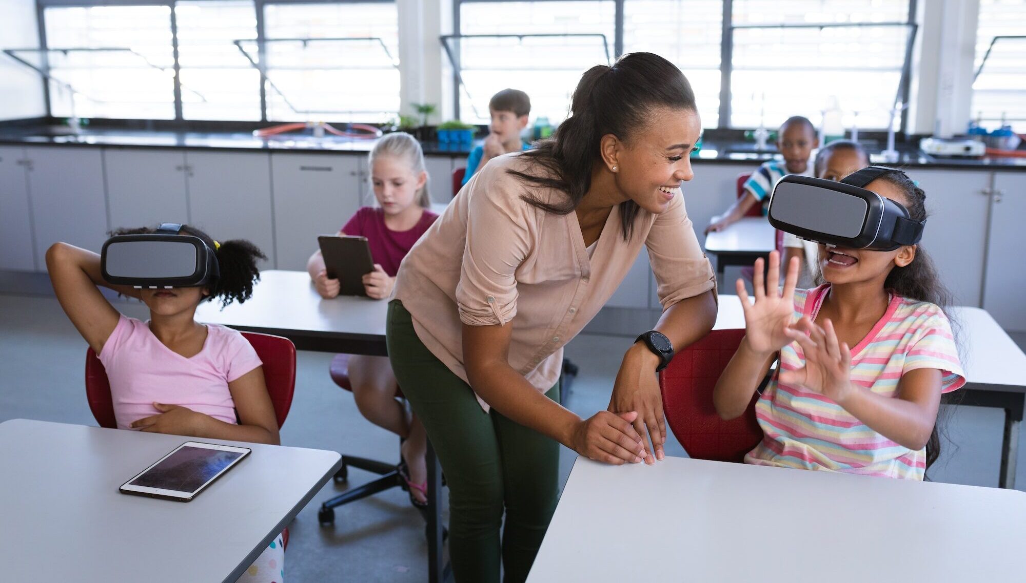 African american female teacher teaching a girl to use vr headset in the class at school