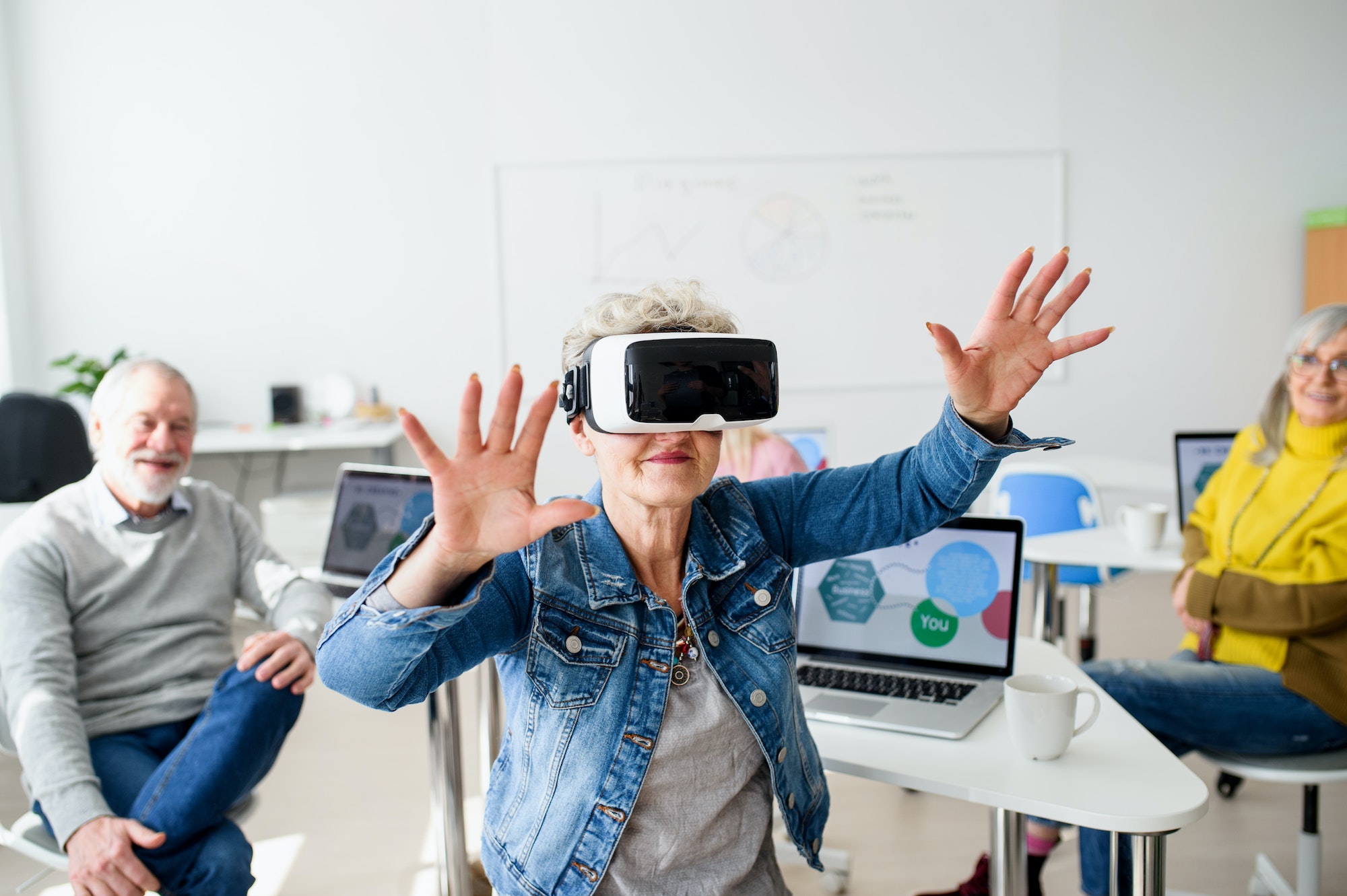 Group of seniors with VR goggles on computer and technology education class